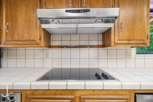 kitchen featuring ventilation hood, brown cabinetry, tile countertops, and black electric stovetop
