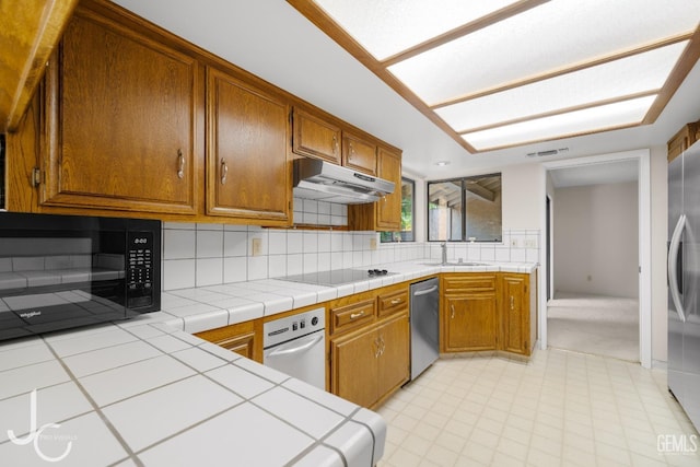 kitchen with brown cabinets, a sink, under cabinet range hood, visible vents, and black appliances