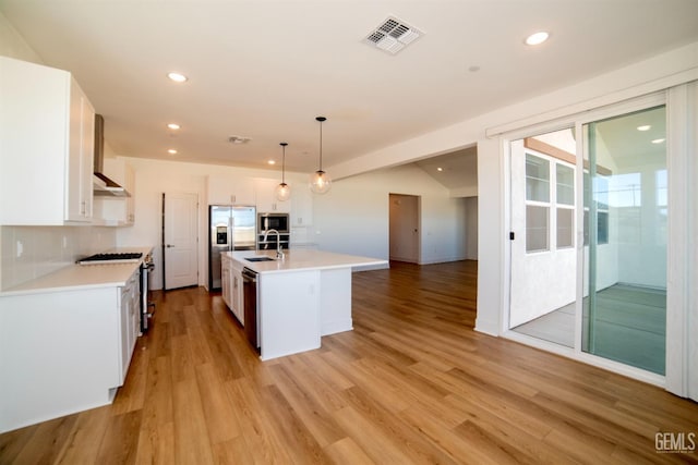 kitchen featuring sink, a center island with sink, hanging light fixtures, appliances with stainless steel finishes, and white cabinets