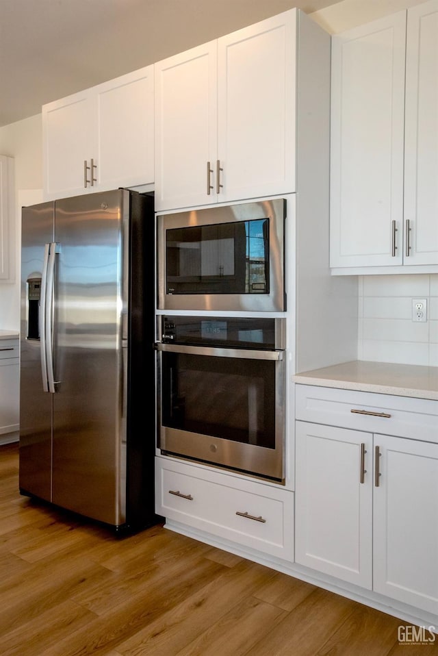 kitchen featuring stainless steel appliances, white cabinetry, and light hardwood / wood-style floors