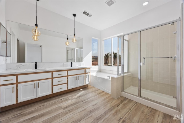 bathroom featuring hardwood / wood-style flooring, vanity, and separate shower and tub