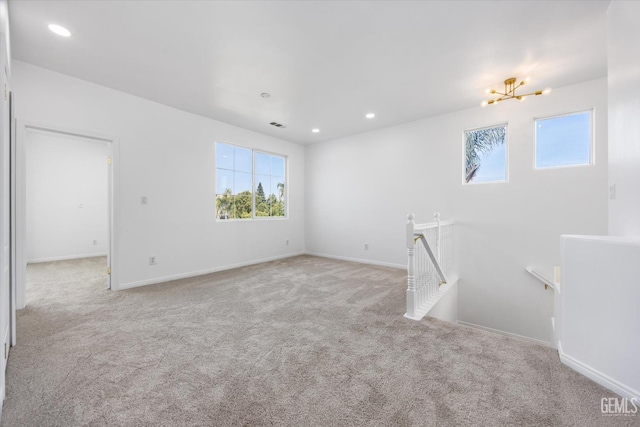 unfurnished room with light carpet and a chandelier