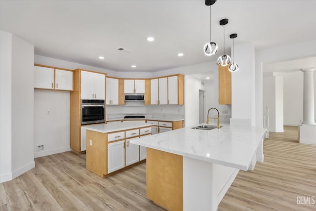 kitchen featuring pendant lighting, sink, light hardwood / wood-style floors, kitchen peninsula, and stainless steel appliances