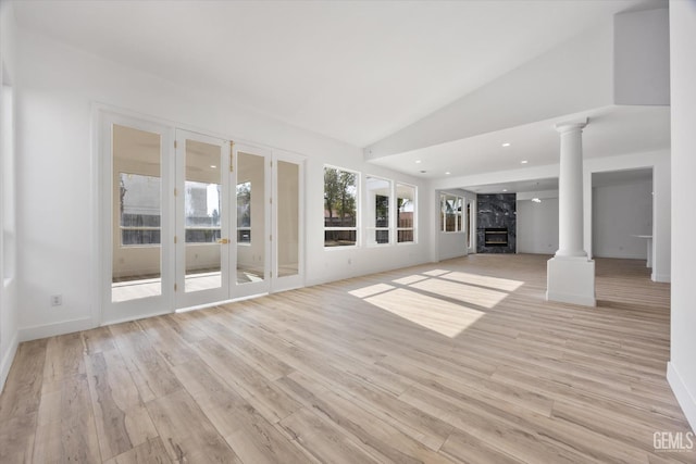 unfurnished living room with ornate columns, high vaulted ceiling, a high end fireplace, and light hardwood / wood-style flooring