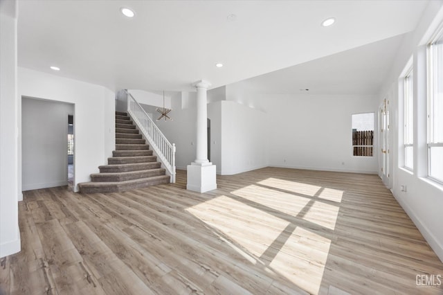 unfurnished living room featuring light hardwood / wood-style flooring and decorative columns