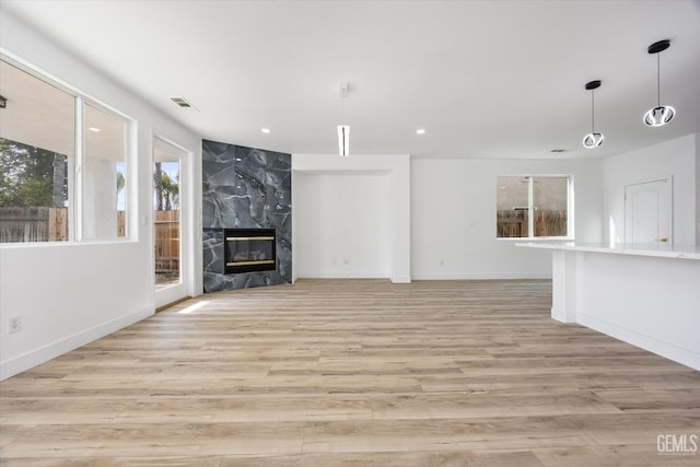 unfurnished living room featuring a high end fireplace and light wood-type flooring