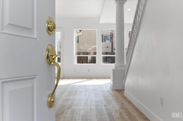 hallway featuring ornate columns and light hardwood / wood-style floors