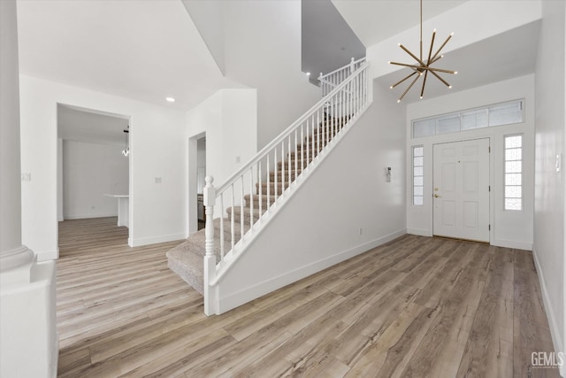 entrance foyer with a high ceiling, a notable chandelier, and light wood-type flooring