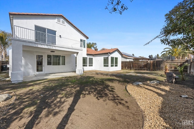 rear view of property featuring a balcony and a patio area