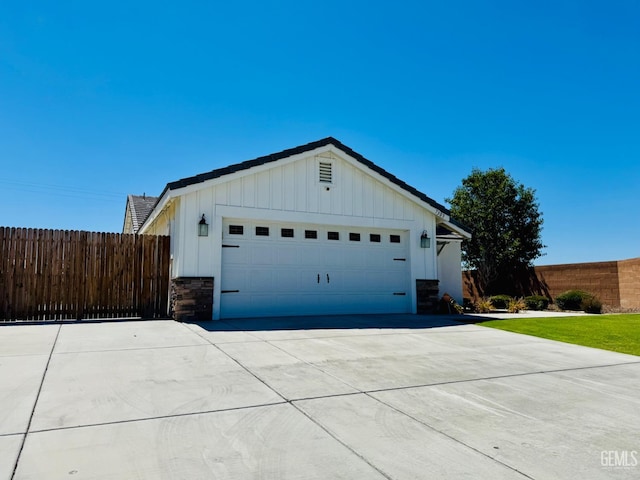 7303 Wild Mustang Dr, Bakersfield, CA 93311 - view of front of house with board and batten siding, stone siding, concrete driveway, and a garage