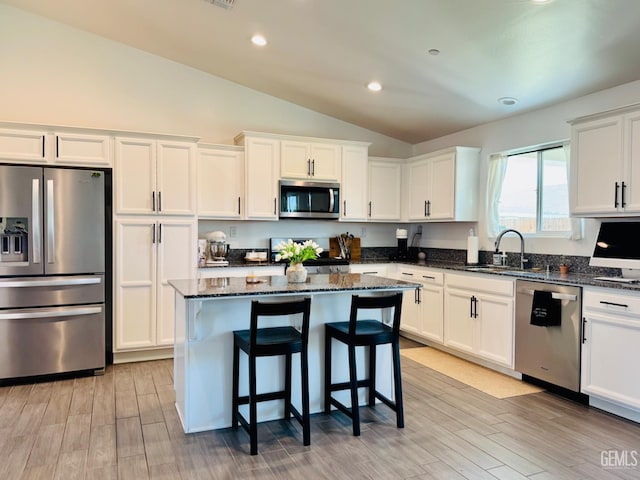 7303 Wild Mustang Dr, Bakersfield, CA 93311 - kitchen featuring stainless steel appliances, lofted ceiling, white cabinetry, dark stone counters, and a kitchen island