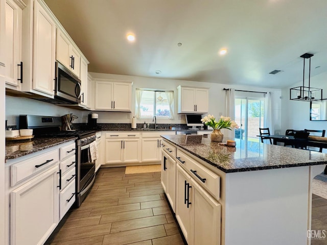 7303 Wild Mustang Dr, Bakersfield, CA 93311 - kitchen with appliances with stainless steel finishes, a kitchen island, white cabinets, wood finish floors, and recessed lighting
