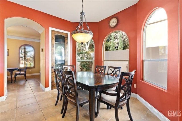 dining area featuring arched walkways, light tile patterned floors, and baseboards