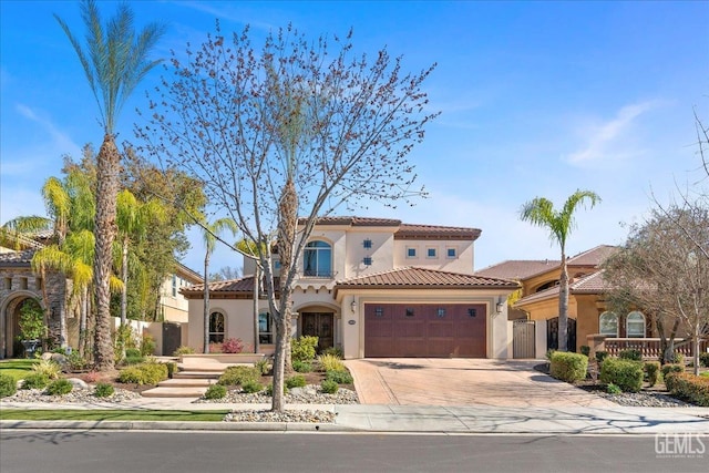 mediterranean / spanish-style house with stucco siding, a tile roof, fence, concrete driveway, and an attached garage