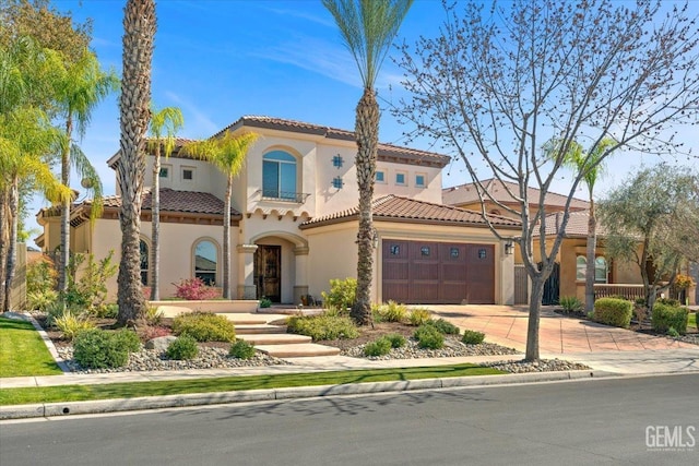 mediterranean / spanish-style home featuring a tile roof, an attached garage, driveway, and stucco siding