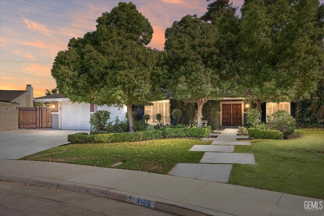 view of property hidden behind natural elements with a garage and a yard