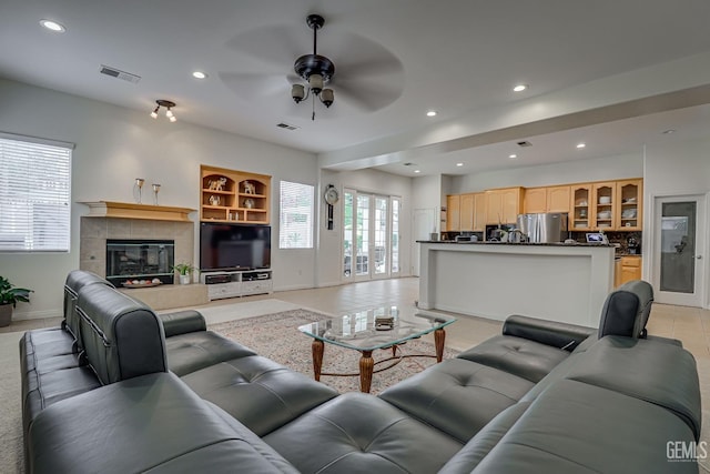 living room with ceiling fan and a tiled fireplace