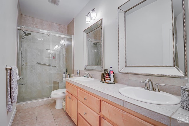 bathroom featuring tile patterned flooring, vanity, toilet, and a shower with door