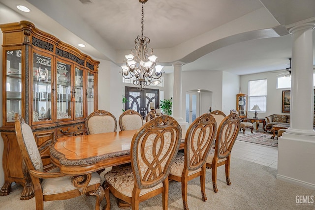 carpeted dining area with ornate columns, french doors, and ceiling fan with notable chandelier