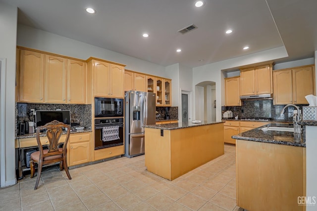 kitchen with black appliances, a kitchen island, dark stone countertops, and sink