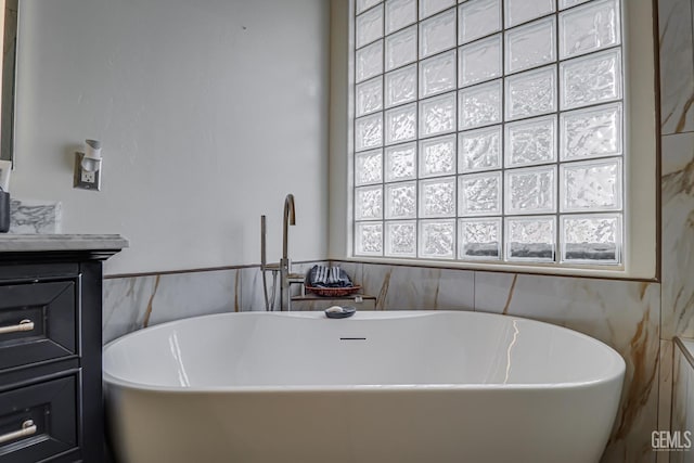 bathroom with a tub to relax in, vanity, and tile walls