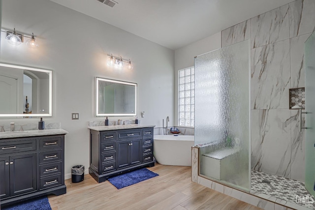 bathroom with hardwood / wood-style floors, vanity, and independent shower and bath