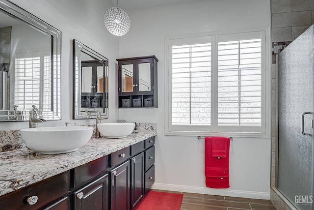 bathroom with vanity, a shower with shower door, and a healthy amount of sunlight