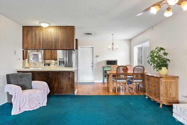 kitchen with appliances with stainless steel finishes, pendant lighting, a textured ceiling, and kitchen peninsula