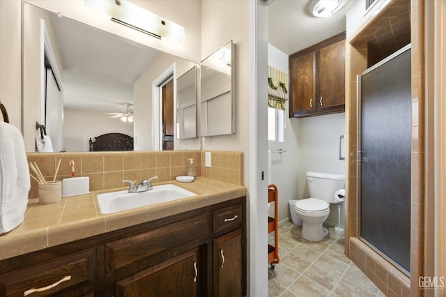 bathroom with vanity, a shower with shower door, backsplash, and toilet