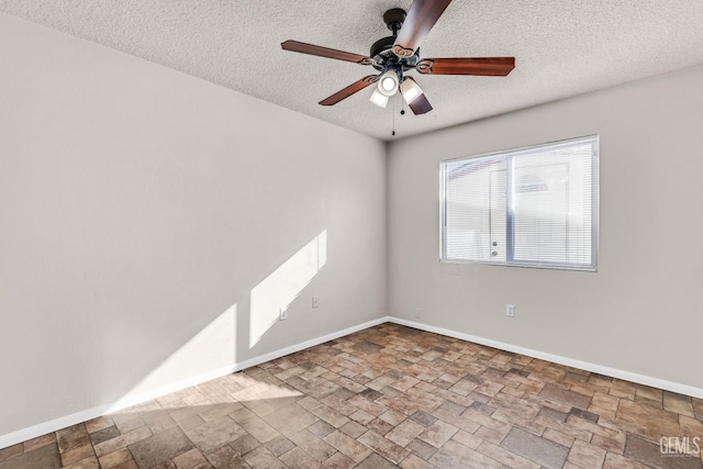 empty room with ceiling fan and a textured ceiling