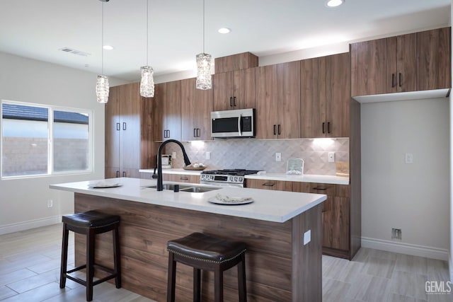 kitchen with pendant lighting, sink, a breakfast bar area, and appliances with stainless steel finishes