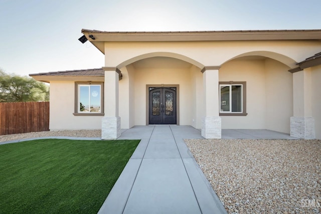 property entrance with a lawn and french doors