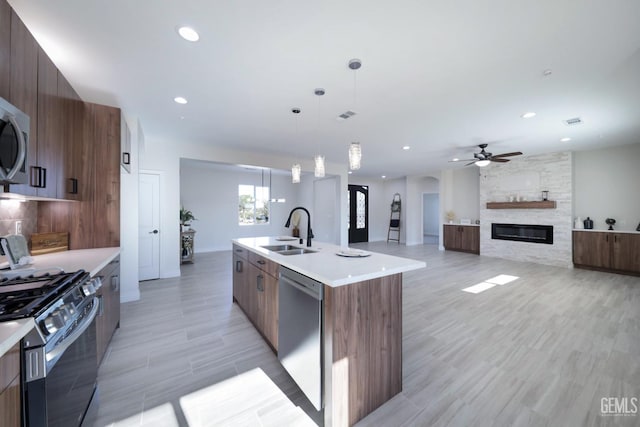 kitchen with a kitchen island with sink, sink, stainless steel dishwasher, decorative light fixtures, and black range with gas cooktop