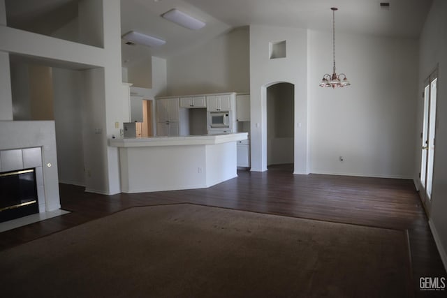 5808 Greenhorn Mountain Ct, Bakersfield, CA 93313 - unfurnished living room featuring high vaulted ceiling, a chandelier, dark wood-type flooring, a tile fireplace, and arched walkways