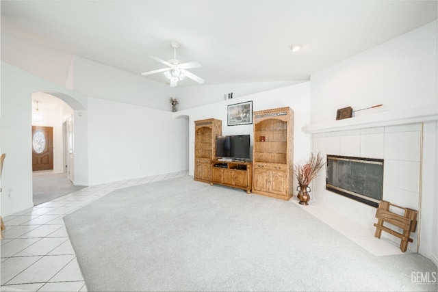 living room with a tiled fireplace, light tile patterned floors, lofted ceiling, and ceiling fan