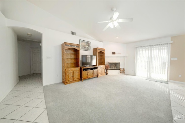 carpeted living room featuring ceiling fan, vaulted ceiling, and a tile fireplace