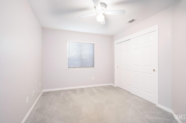 unfurnished bedroom with ceiling fan, light colored carpet, and a closet