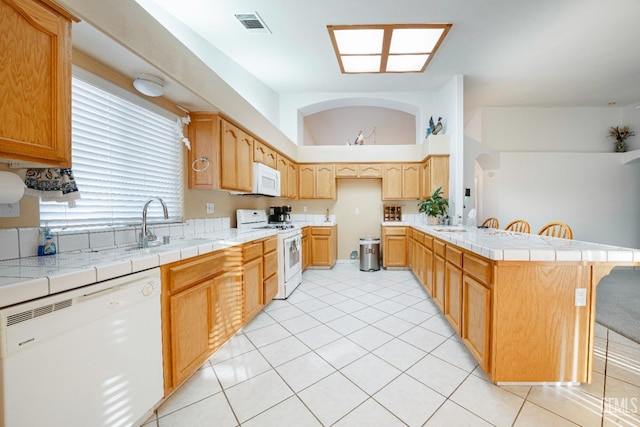 kitchen with white appliances, tile countertops, a breakfast bar area, and light tile patterned floors