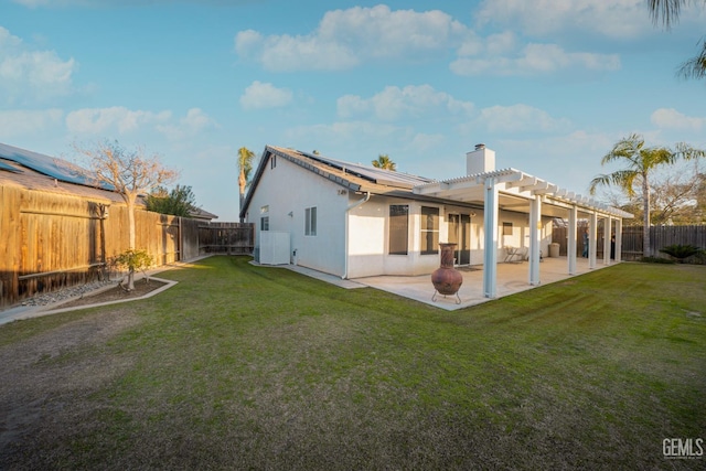 rear view of property featuring a pergola, solar panels, a patio area, and a lawn