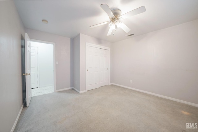 unfurnished bedroom with ceiling fan, light carpet, and a closet