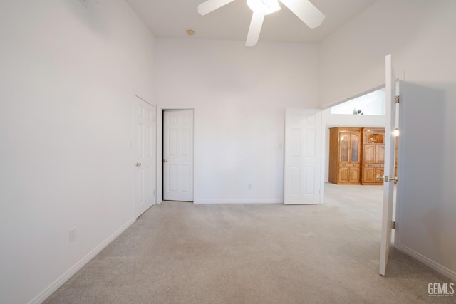 carpeted spare room featuring ceiling fan and a high ceiling