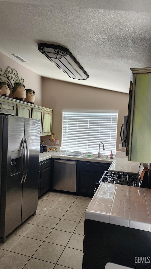 3808 Mariana Way, Bakersfield, CA 93311 - kitchen with stainless steel appliances, tile counters, a sink, light tile patterned flooring, and a textured ceiling