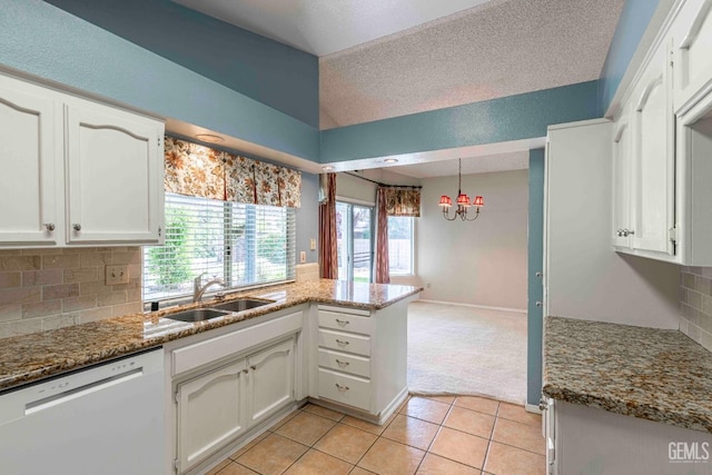 kitchen with a peninsula, white cabinetry, a sink, white dishwasher, and a notable chandelier