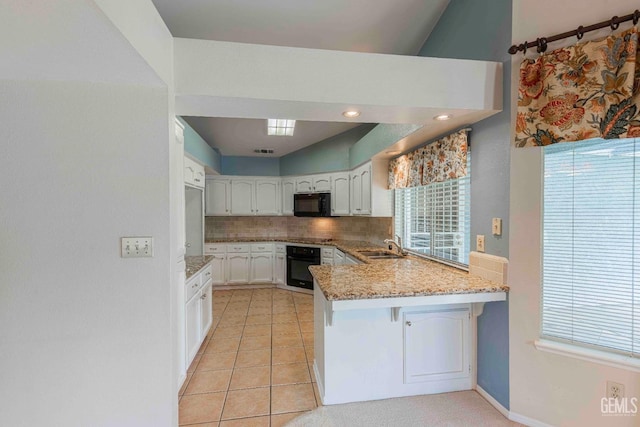 kitchen featuring light stone counters, a peninsula, white cabinets, decorative backsplash, and black appliances