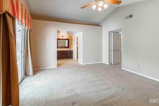 unfurnished bedroom featuring baseboards, light carpet, ensuite bath, visible vents, and lofted ceiling