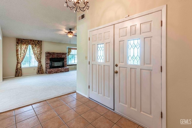 entryway featuring light carpet, a wealth of natural light, light tile patterned floors, and a fireplace