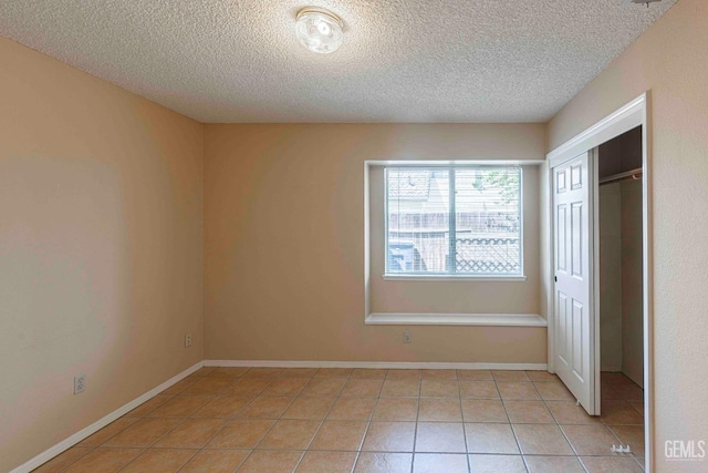 unfurnished bedroom with a textured ceiling, a closet, and light tile patterned floors
