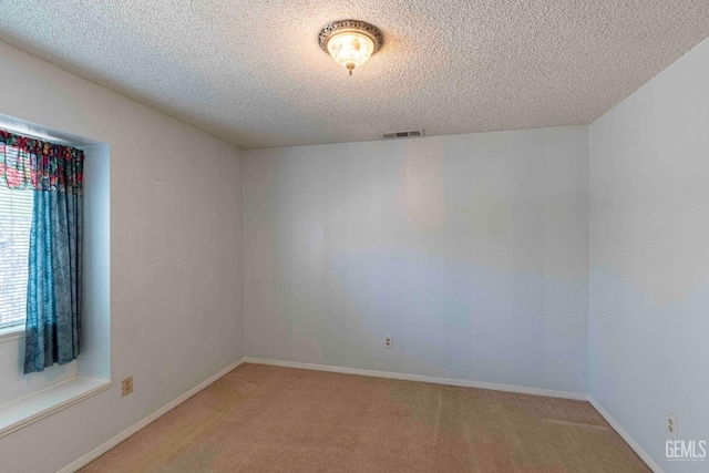 spare room with a textured ceiling, baseboards, light carpet, and visible vents