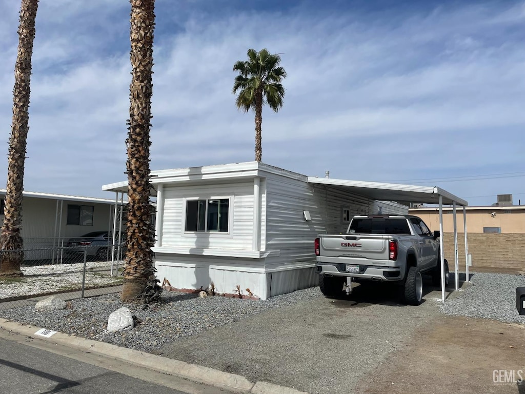 4401 Hughes Ln Unit 116, Bakersfield, CA 93304 - manufactured / mobile home with an attached carport and gravel driveway