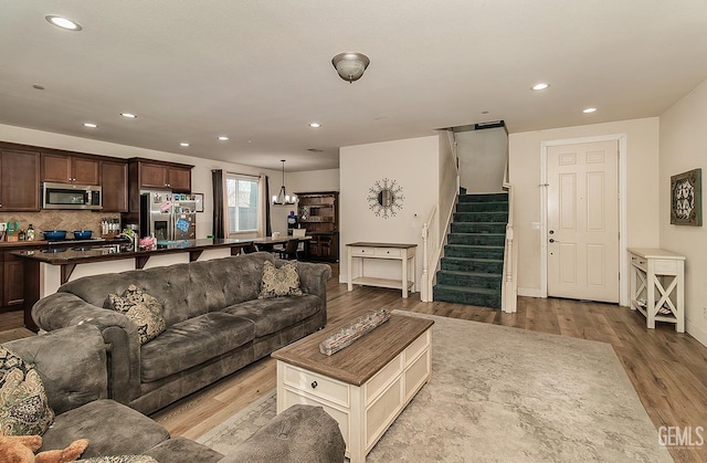 living room with baseboards, light wood finished floors, stairway, and recessed lighting